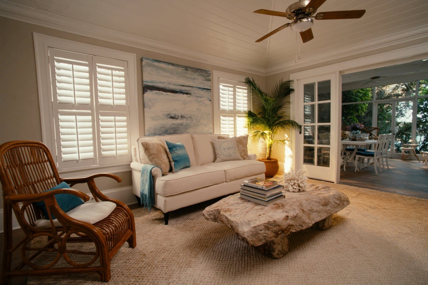 Bright coastal living room of a Cozy Corner rental, opening onto a screened lanai